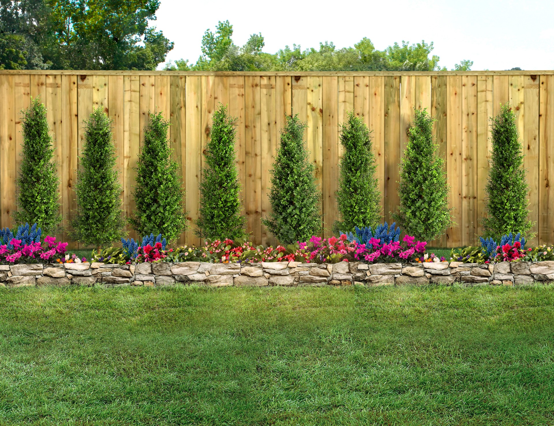 Empty backyard with green grass, trees, flowers and wood fence